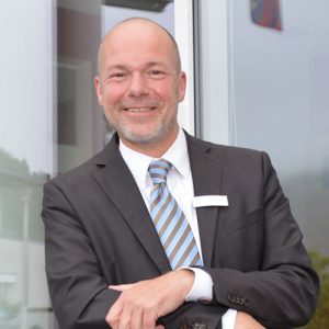 Stephan Bode, the CEO of the hotel SCHWARZWALD PANORAMA is smiling in front of a hotel door