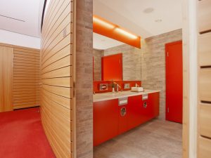 An orange bathroom with a wooden exterior and brickwalls inside, as a part of the conference services of the hotel SCHWARZWALD PANORAMA