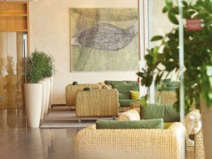 A lounge are with multiple couches, plants and a large painting on the wall, at the wellnesshotel SCHWARZWALD PANORAMA