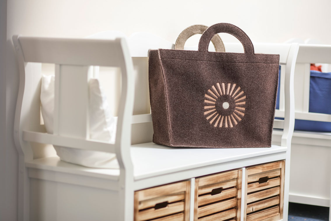 A bag with the Schwarzwald Panorama logo made from brown fabric resting on a white wooden bench.