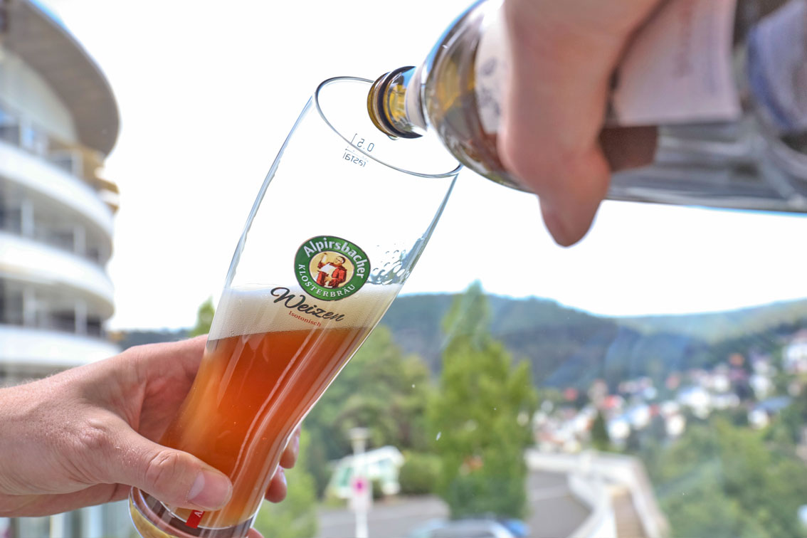 A beer being poured into a glas in front of the Hotel Schwarzwald Panorama