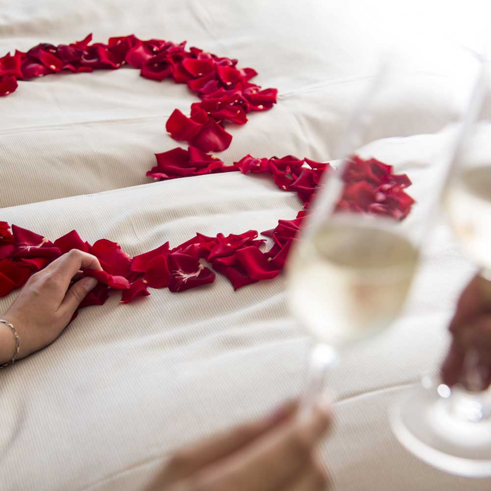 Mit Rosenblüten dekoriertes Bett in der Hochzeitssuite
