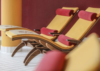 Holzliegestühle mit orangen und roten Polstern stehen im Spa und Wellness Bereich des Hotel Schwarzwald Panorama