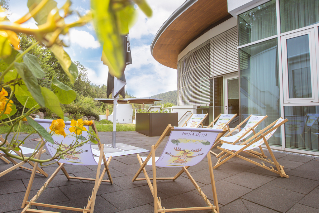 Auf einer Steinterrasse stehen Liegestühle vor grüner Kulisse im Hotel Schwarzwald Panorama
