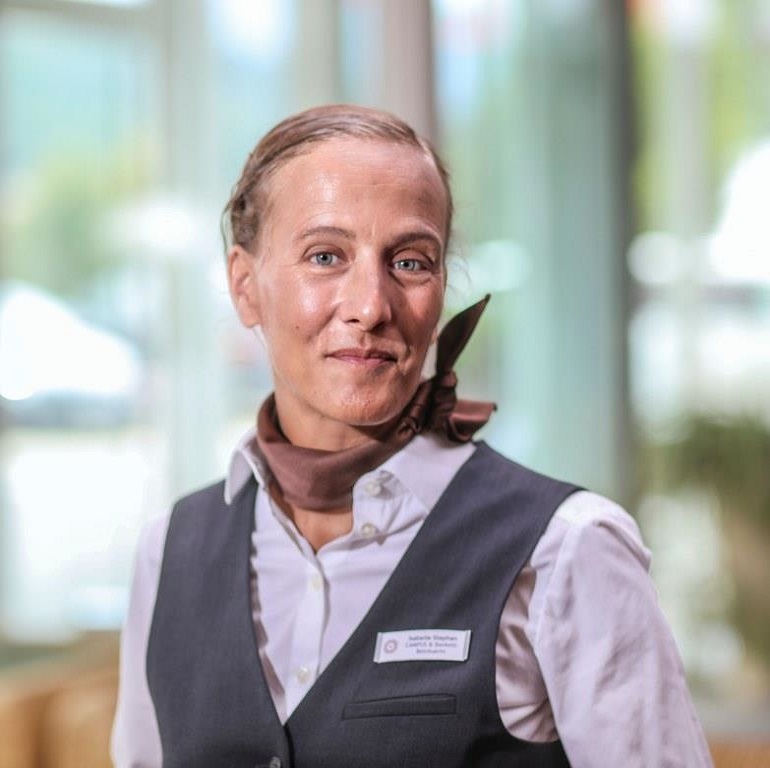 Frau Stephan vor einem beleuchteten Fenster, Sie ist Verkaufskoordinatorin im Hotel Schwarzwald Panorama