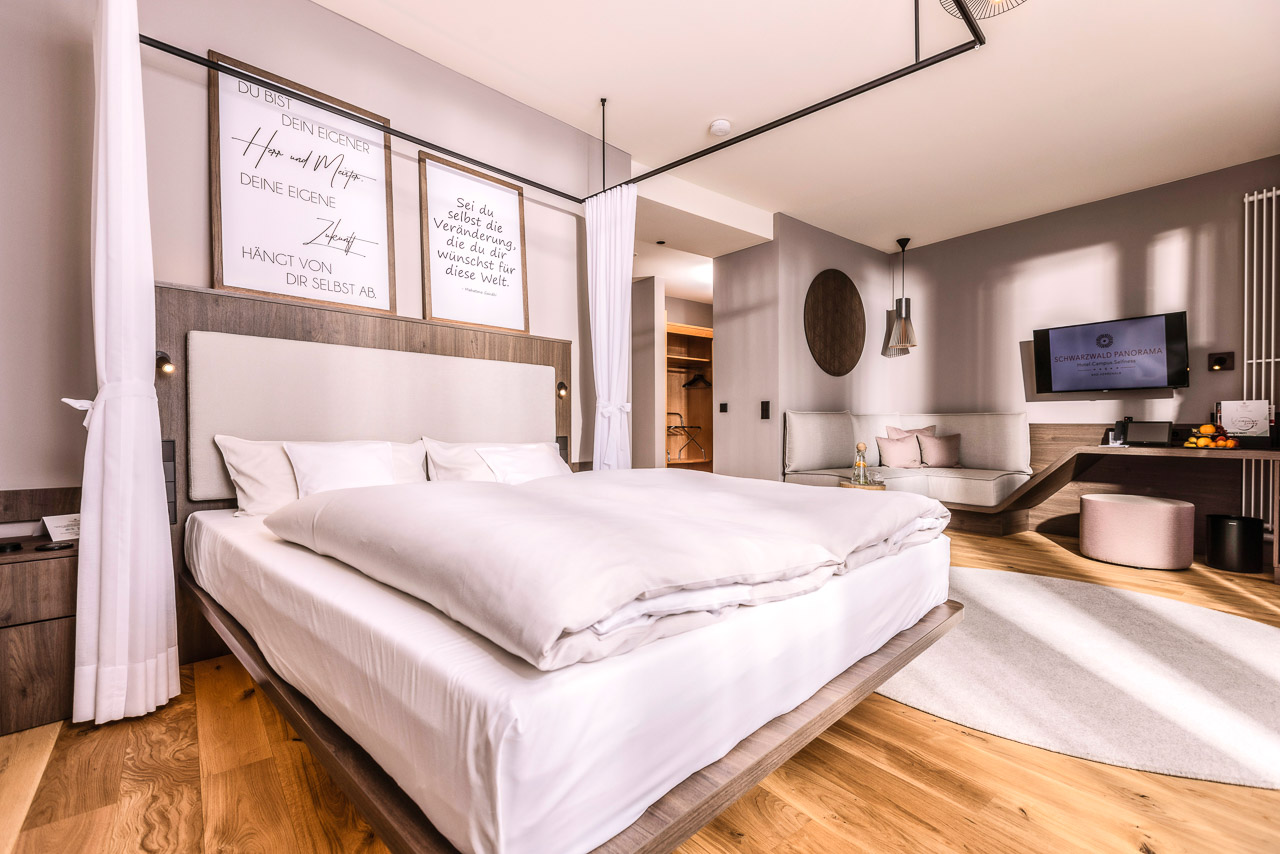 Ein Foto des CIRCULAR LIVING-Zimmers Freigeist mit Bett, Betthimmel und zwei großen Bilderrahmen.